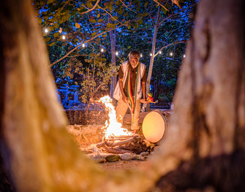 Rastafarian Shaman building a fire surrounded by trees