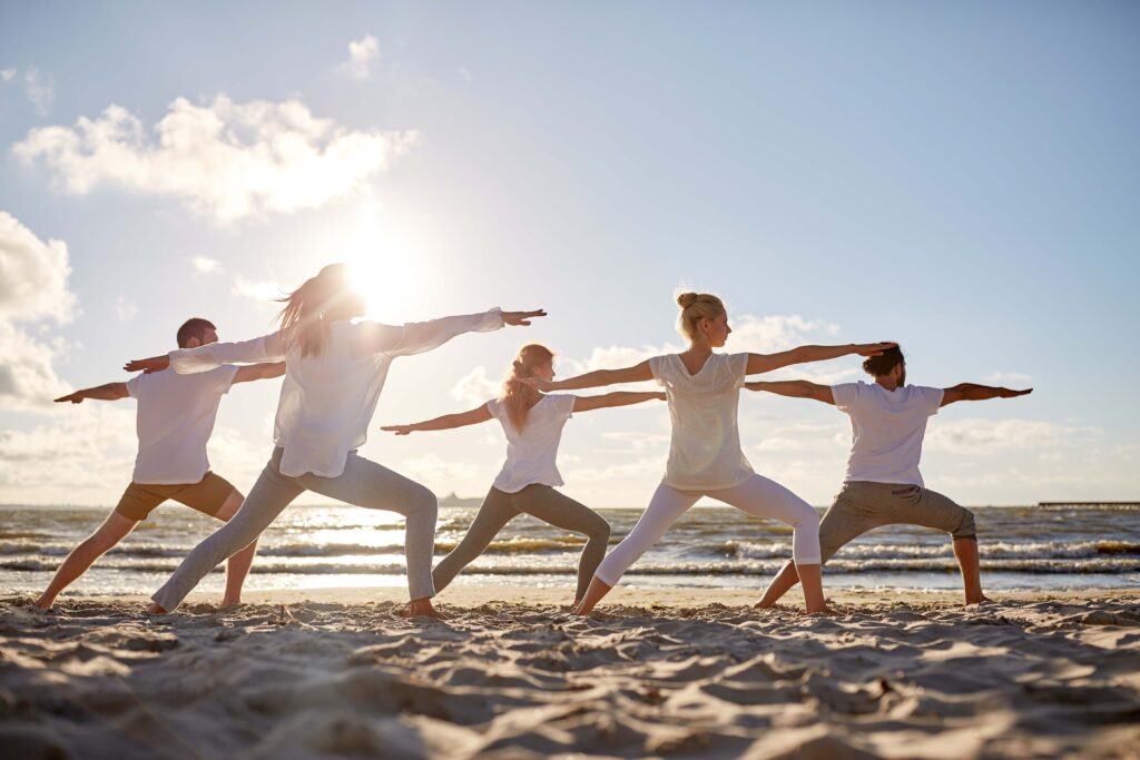 Group of people practicing yoga on the beach