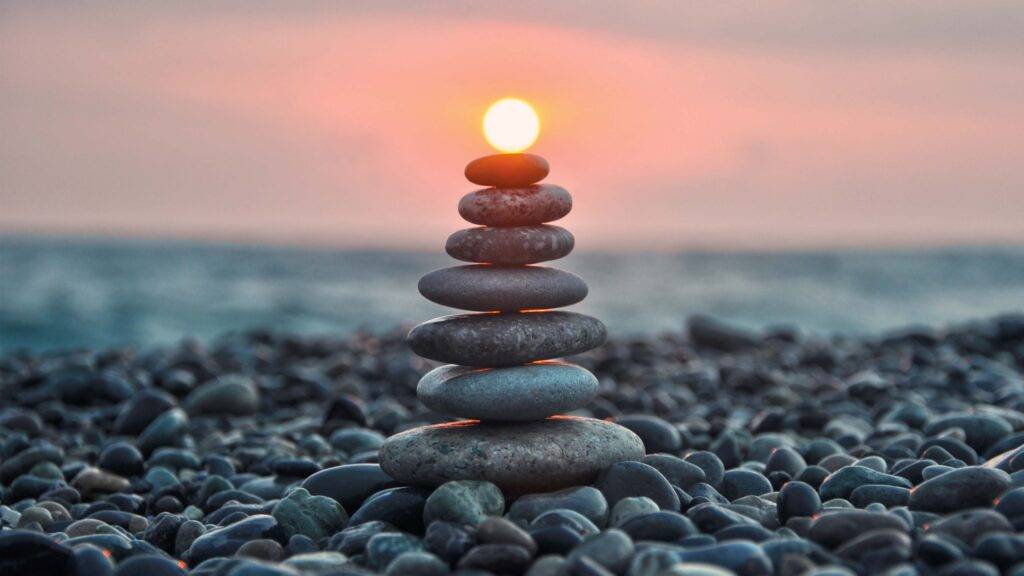 Zen balancing rock sculpture aligned with sunset