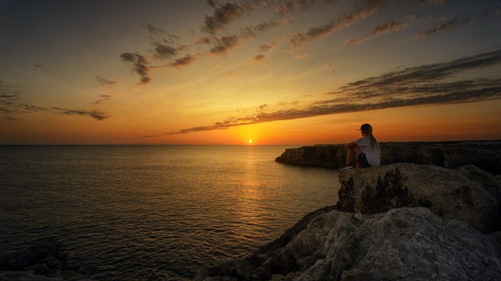 Person sitting on a rock watching the sunset